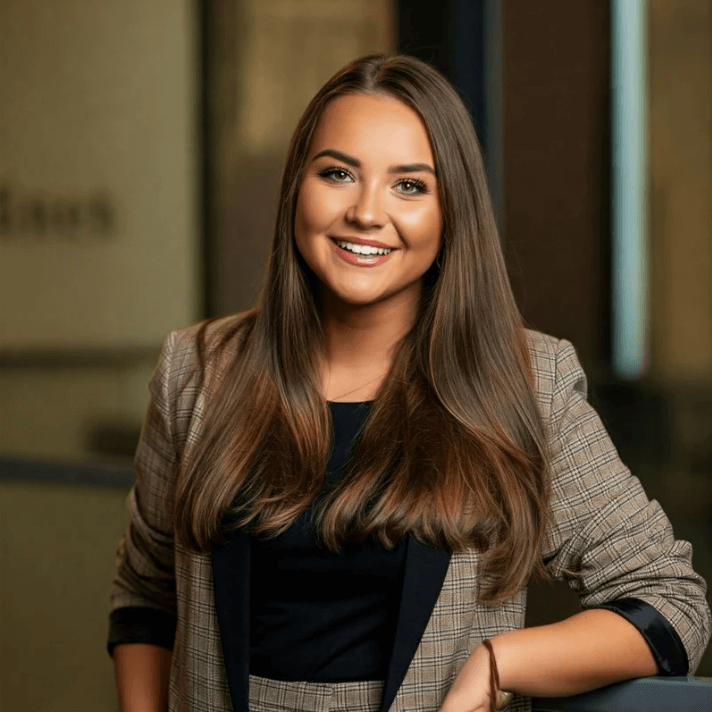 Portrait of a smiling woman in a gray blazer, showcasing professional style and confidence.
