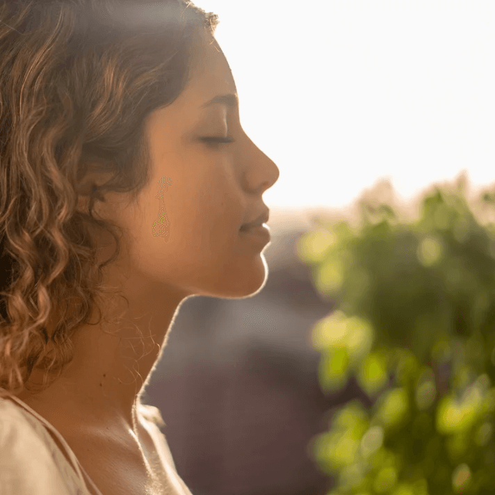 Femme utilisant le Roller ultra apaisant avec un sourire, visage détendu et lumière naturelle.