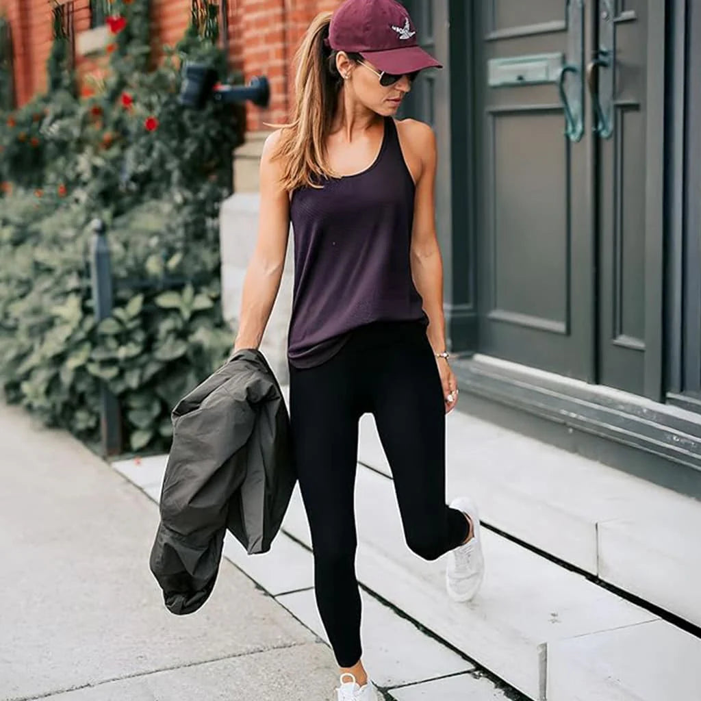 Femme portant des leggings Éclat Bio SilhouetteFlex avec un haut noir et une casquette, marchant sur des escaliers.